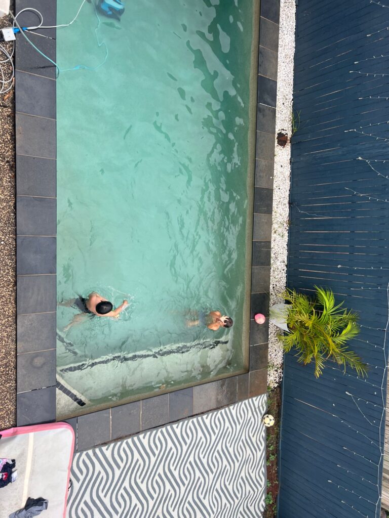 Looking down on two boys swimming in a backyard pool, practising the day before their school swimming carnival.